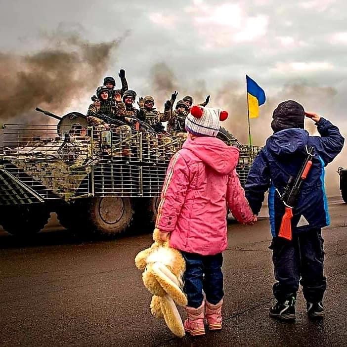 Children watching soldiers drive by